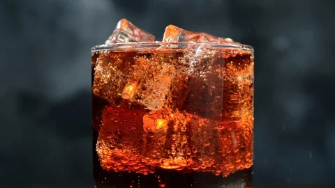 Cola with Ice cubes and bubbles in glass, macro footage. Fizzing soda drink Stock Footage 129638254