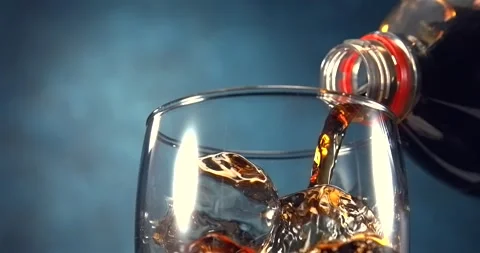 Cola pouring into glass with ice cubes in slow motion on blue background Stock Footage 346226091
