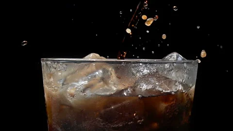 Cola Pouring Over Ice Cubes in Glass, Close Up on Black Background Stock Footage 346088304