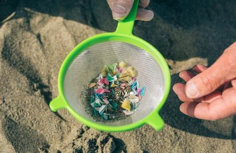 Colander with microplastics on the beach Stock Photos