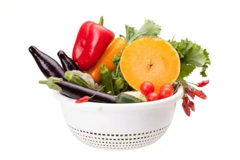 Colander with vegetables on white Stock Photos