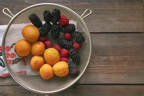 Colander with the washed-up berries raspberry and blackberry and apricots Stock Photos