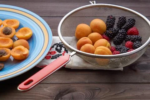 Colander with the washed-up berries raspberry and blackberry and apricots Stock Photos