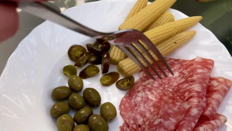 Cold appetizer. Salami, corn, olives and spicy jalapeno pepper on white plate Vidéo 252019044