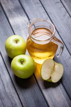 Cold apple juice in pitcher on table, vertical top view morning still life Stock Photos