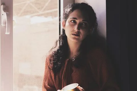 Cold autumn days - young multi-racial female drinks coffee in a cozy windowsill Stock Photos