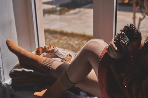 Cold autumn days - young multi-racial female drinks coffee in a cozy windowsill Stock Photos