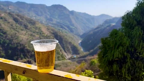 Cold Beer on Balcony Railing with Stunning Mountain Valley Background Stock Footage 332615696