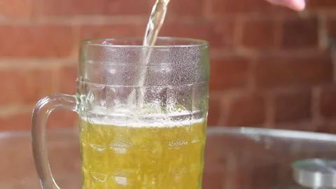 Cold beer from a dark bottle is poured into a large mug Stock Footage 134861445