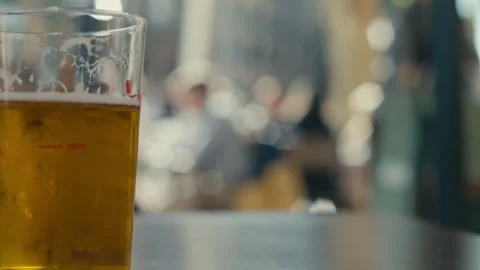 Cold Beer Glass On Cafe Table With Vibrant City Life in Background Stock Footage 333693174