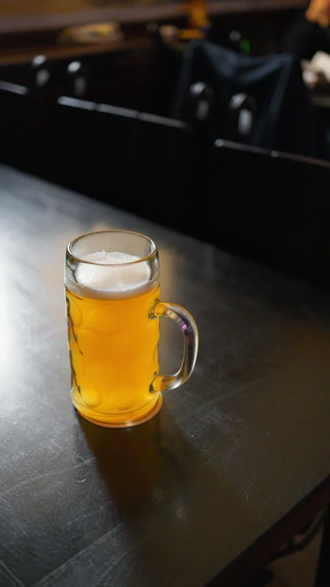 Cold beer in glass mug on dark bar table with soft reflections and blurred Stock Footage 337648319