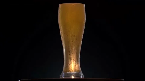 Cold beer in glass rotate in surface with black background. Detail Shot of Beer Stock Footage 151467233