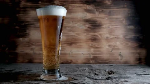 Cold beer in glass with a white cap of Foam and bubbles. Stock footage Stock Footage 133733739