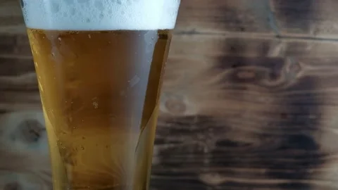 Cold beer in glass with a white cap of Foam and bubbles. Stock footage Stock Footage 133734023