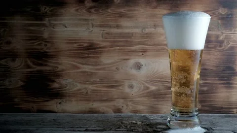 Cold beer in glass with a white cap of Foam and bubbles. Stock footage 動画素材 133735268
