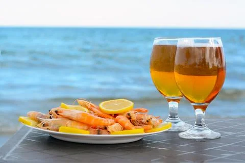 Cold beer in glasses and shrimps served with lemon on beach Stock Photos