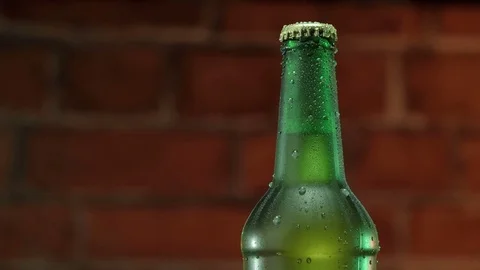 Cold beer in a green bottle with water drops on brick wall Stock Footage 77823941