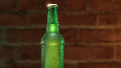 Cold beer in a green bottle with water drops on brick wall Stock Footage 77824543