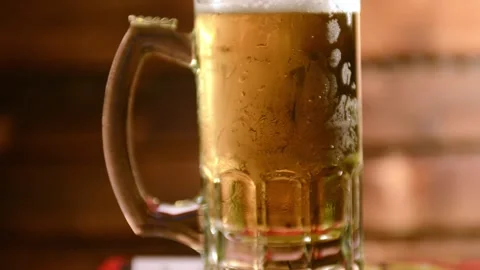 Cold Beer poured in to mug shot against wooden background 動画素材 145864097