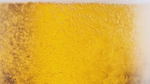 Cold beer is poured into a rotating beer glass Stock Footage 125637957