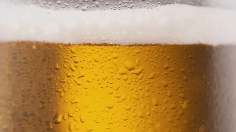 Cold beer is poured into a rotating beer glass Stock Footage 125638118