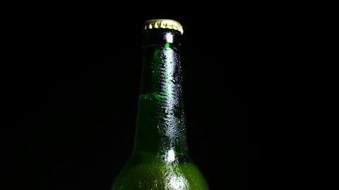 Cold beer with water drops on bottle is illuminated by light from the darkness Stock Footage 153656907