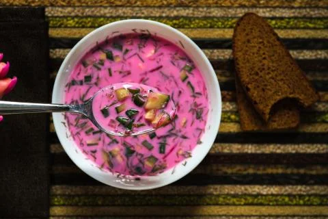 Cold beetroot soup on a spoon in your hand and bread on a decorative tray.Sou Fotos Stock