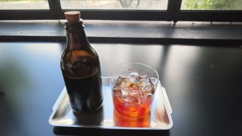 Cold brew coffee bottle and iced cocktail resting Stock Footage 344746810