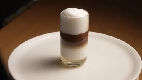 Cold brew coffee with ice cubes and milk spinning on a white plate, perfect for Vídeos de archivo 339152723