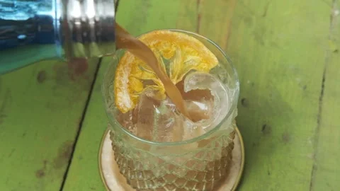 Cold brew coffee is poured from bottle into glass filled with ice. Video stock 150151091