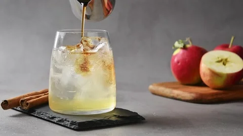 Cold brew coffee pours over apple cider tonic and ice, creating layered Stock Footage 345557520