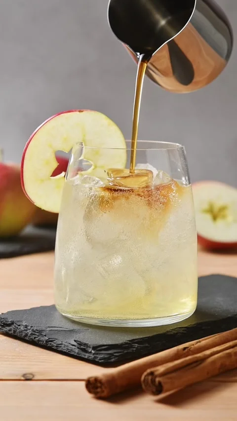 Cold brew coffee pours over apple cider tonic and ice, creating layered drink in Stock Footage 345558256