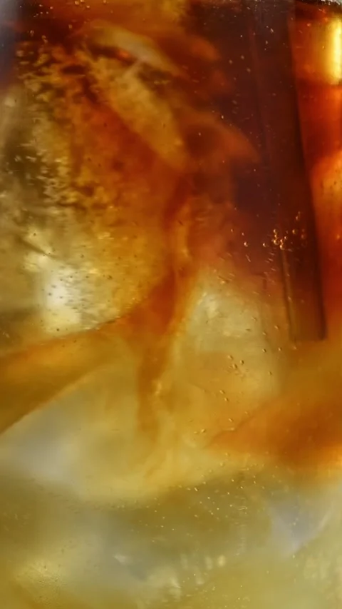 Cold brew mixes with sparkling apple cider and tonic around ice as drink is Stock Footage 345487133
