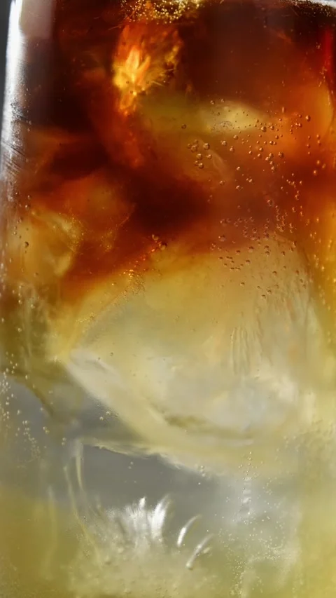 Cold brew slowly swirls through sparkling apple cider and tonic around ice in Stock Footage 345487006