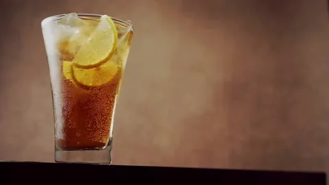 Cold brown drink with ice cubes and lemon slices Stock Footage 135699324