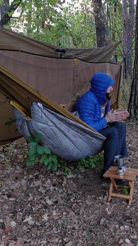 Cold Camper Sitting In Hammock Rubbing Hands On Chilly Morning Stock Footage 346550391