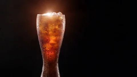 Cold cola with ice in a glass on a black background Stock Footage 76999201