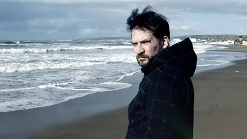 Cold color correction of strong bad man in front of sea looking criminal sad  Stock Footage 118392893