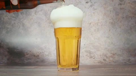 Cold craft  light Beer is pouring from bottle on wooden Table 库存影片 194307083