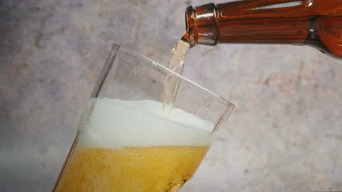 Cold craft  light Beer is pouring from bottle on wooden Table 스톡 동영상 194307234