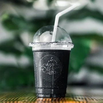 Cold drink in a black plastic Disposable glass on a wooden table Stock Photos