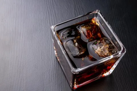 A cold drink with ice on a dark table. A chilled drink in a glass. Stock Photos