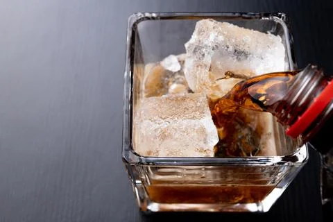 A cold drink with ice on a dark table. A chilled drink in a glass. Stock Photos