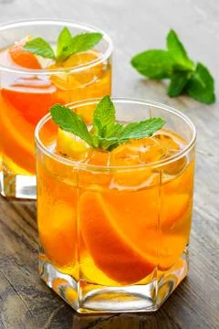 Cold drinks with ice and mint. Orange cocktail on rustic wooden table Stock Photos