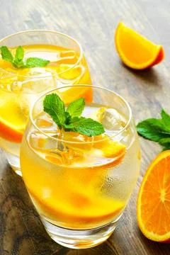 Cold drinks with ice and mint. Orange cocktail on rustic wooden table Foto stock