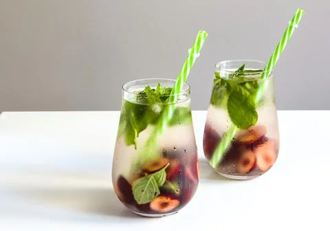 Cold drinks in small bottles. Cherries and mint lemonade. Mojito coctail. Stock Photos