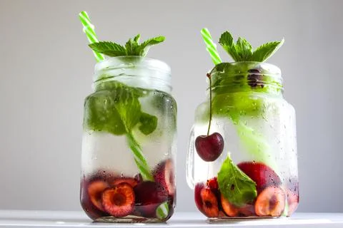 Cold drinks in small bottles. Cherries mint lemonade. Mojito coctail. Stock Photos