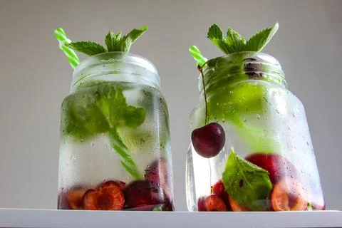 Cold drinks in small bottles. Cherries mint lemonade. Mojito coctail. Stock Photos