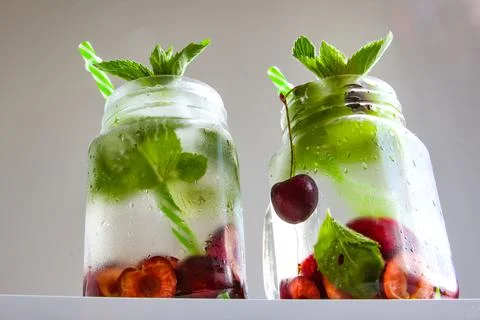 Cold drinks in small bottles. Cherries mint lemonade. Mojito coctail. Stock Photos