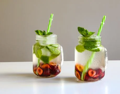 Cold drinks in small bottles. Cherries mint lemonade. Mojito coctail. Stock Photos